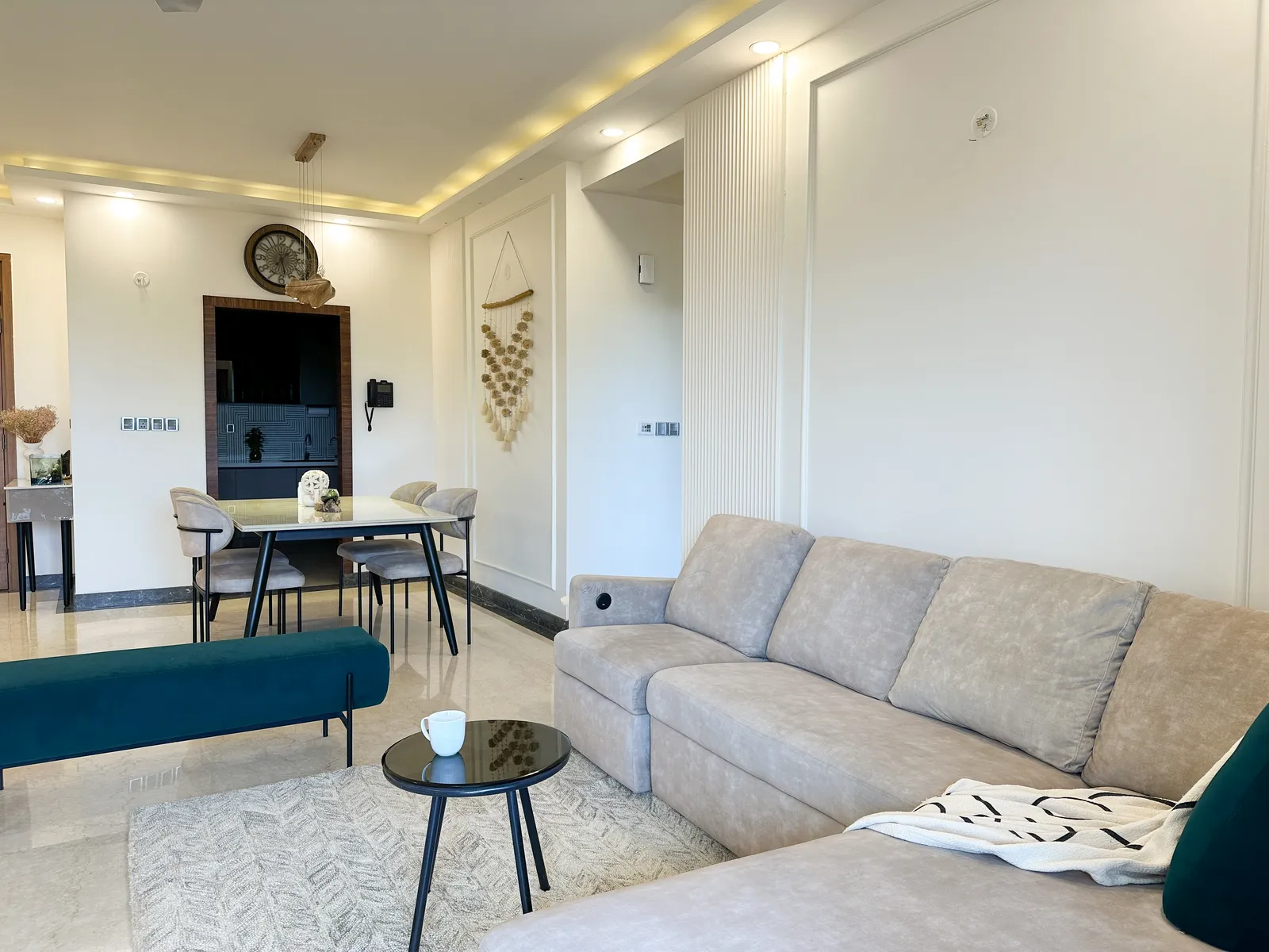 Open living and dining area with grey sectional and panelled walls — Somani's Residence